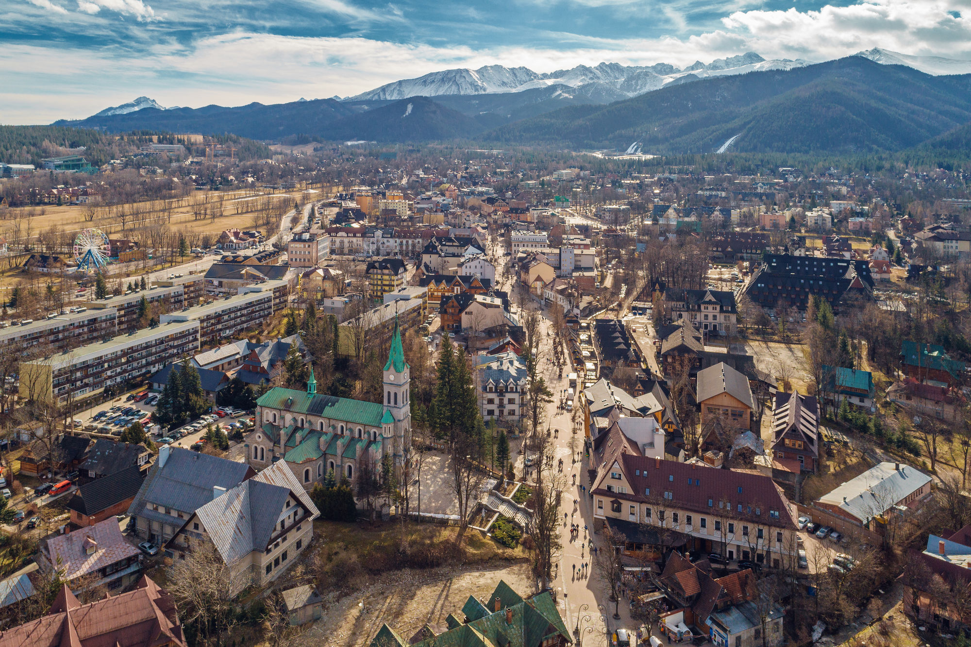 Panorama górskiego miasta z kościołem na pierwszym planie i ośnieżonymi szczytami w tle