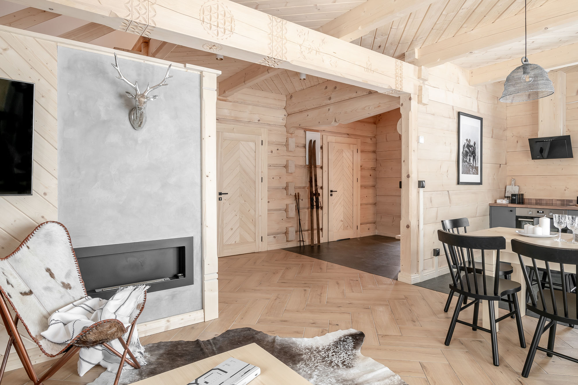 Jasny salon z drewnianym wykończeniem, kominkiem, jadalnią i dekoracją z głową jelenia